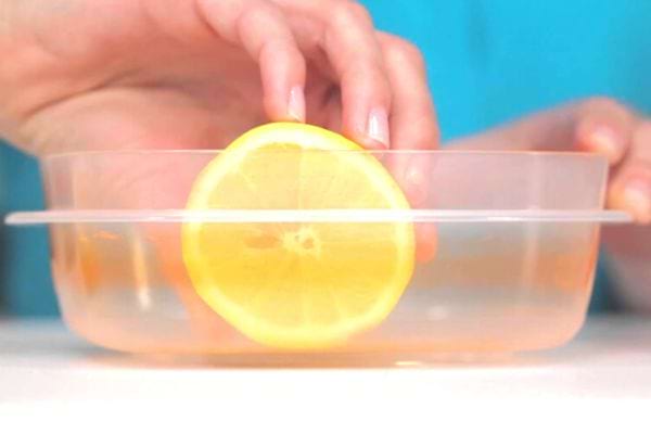 Une personne passant du citron dans un récipient transparent