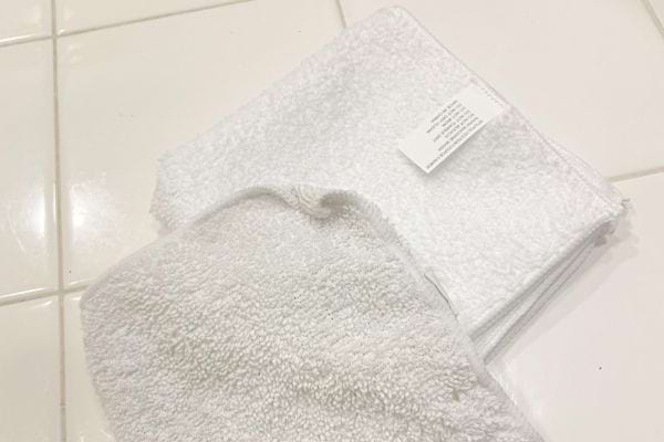 Deux petites serviettes blanches posées sur du carrelage blanc