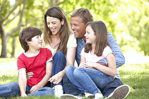 Une famille qui rigole assise dans l'herbe 