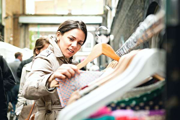 Une femme regardant un vêtement sur un cintre dans une brocante 