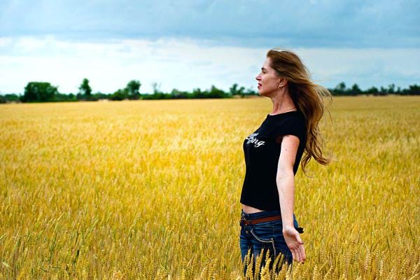 Une femme ouvrant les bras dans un champ