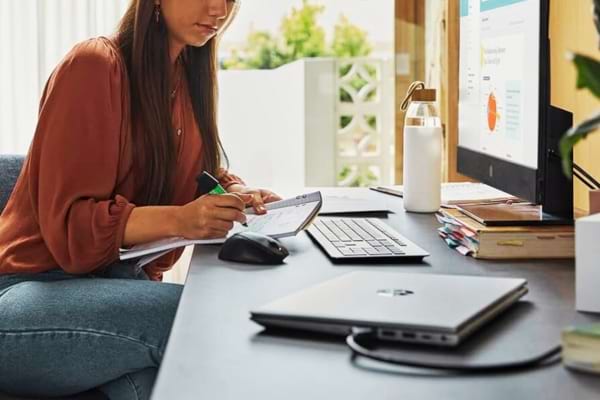 Une femme devant son bureau et son ordinateur qui vend ses créations en ligne