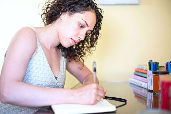Une femme qui est en train d'écrire sur un livre 