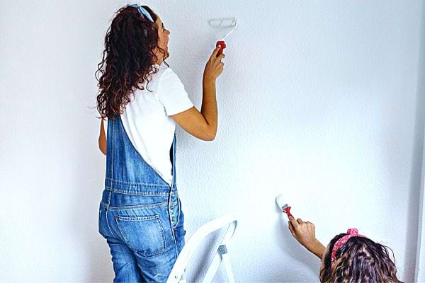 Deux femmes qui font mettent de la peinture sur un mur avec des rouleaux 