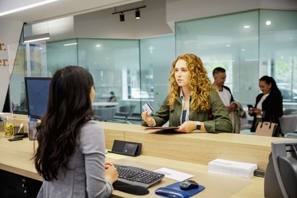Une femme au guichet d'une banque qui veut faire de la monnaie