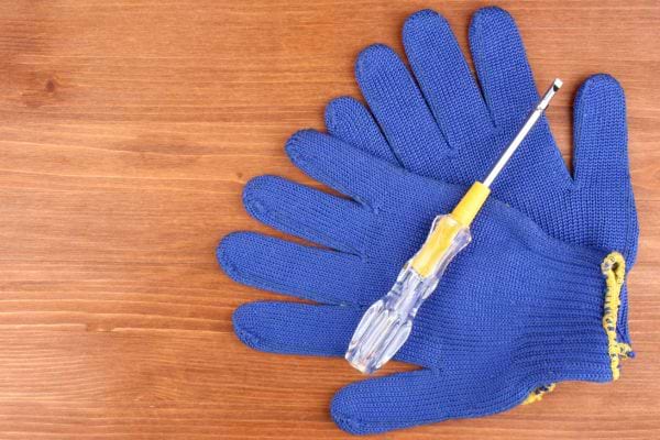 Une paire de gants de protection bleus avec un tournevis jaune dessus 