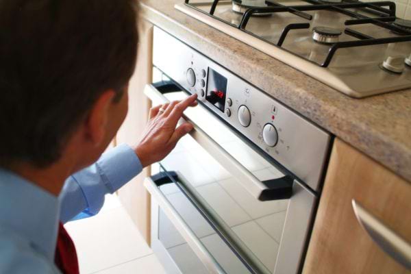 Un homme qui touche aux différentes fonctionnalitées d'un four 