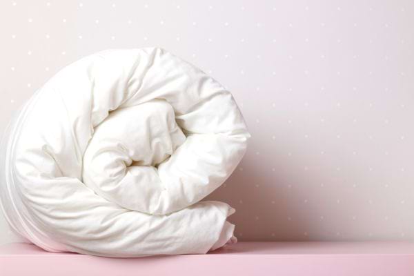 Une grosse couette blanche enroulée sur un espace rose