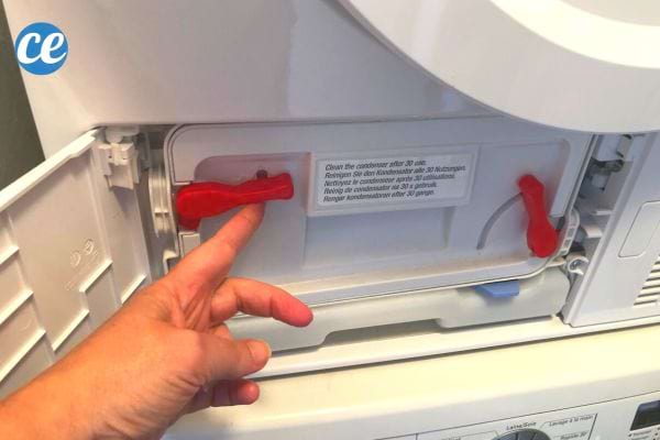 Une personne touchant la petite manivelle rouge d'un condenseur de sèche-linge 