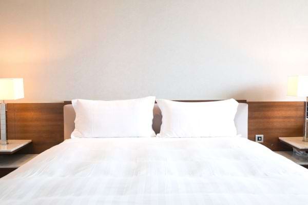 Un lit deux places avec deux oreillers blanc avec une lampe de chevet sur le côté