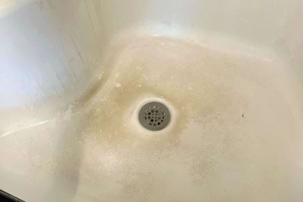 Une baignoire blanche ayant des tâches qui ont noirci la surface 