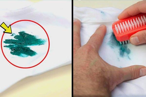 Ein grüner Farbfleck auf einem weißen Kleidungsstück, auf dem eine Person mit einem orangefarbenen Pinsel reinigt