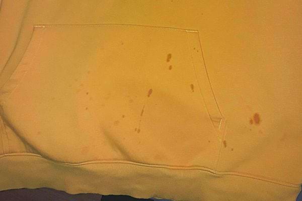 Mehrere kleine Flecken auf einem orangefarbenen Pullover