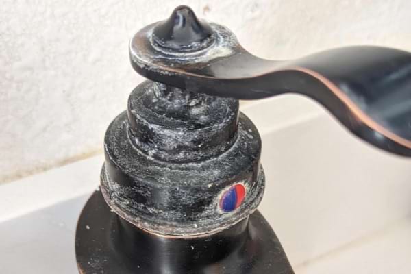 Un robinet noir avec des traces de calcaire