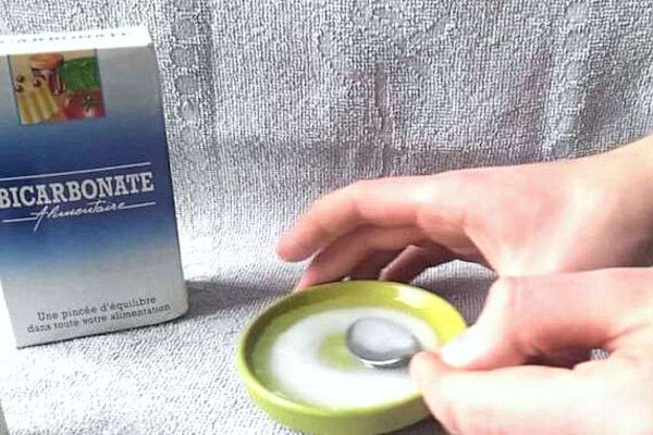 Du bicarbonate dans un couvercle vert avec une cuillère à café 