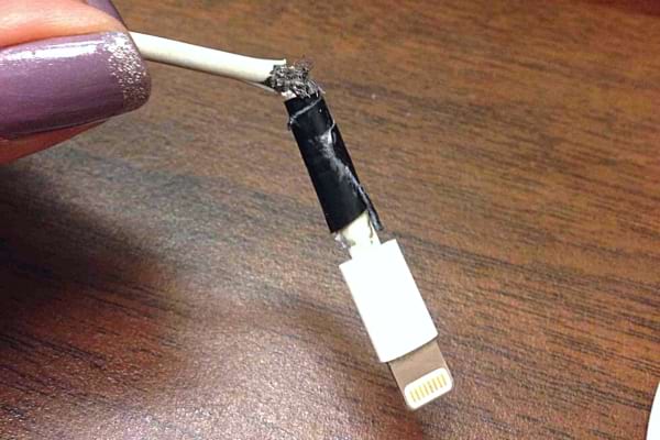 Une femme tenant un chargeur Apple cassé