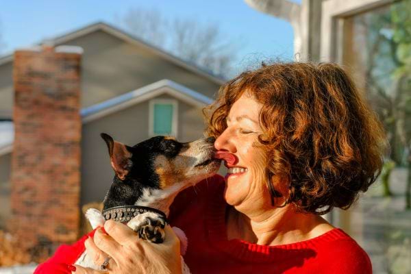 Un chien qui lèche une femme avec un haut rouge