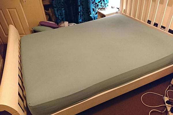 Un lit avec un drap vert