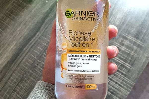 Une personne qui tient une bouteille d'eau micellaire 