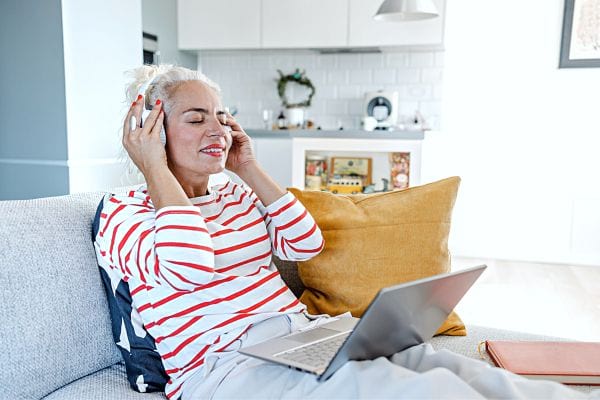 Une femme avec un casque et un ordinatuer sur ses genoux 