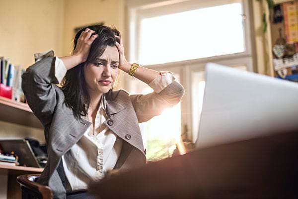 Une femme se tenant la tête devant son ordinateur