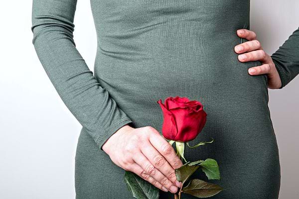Une femme vêtu d'une robe verte tenant une rose