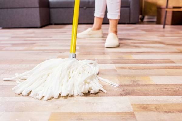 Une femme qui nettoie un sol en pvc avec une serpillère