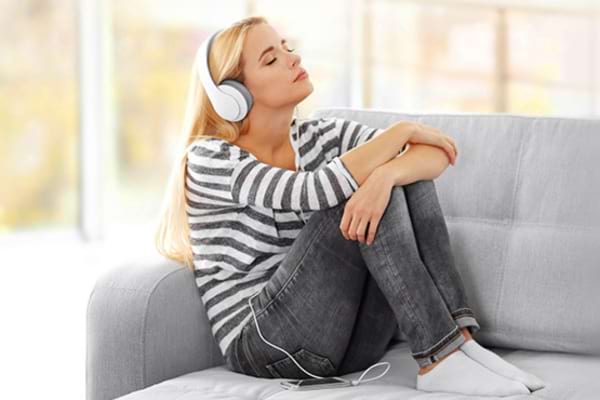 Un femme qui ferme les yeux en écoutant un livre audio gratuit