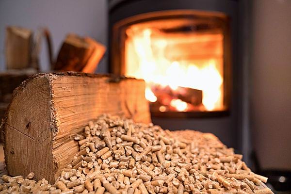 Plusieurs granulés avec du bois de chauffage et une poêle à granulés au second plan