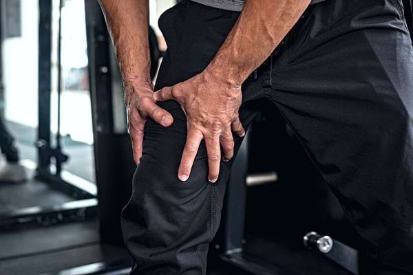 Un homme se tenant la jambe avec un pantalon noir