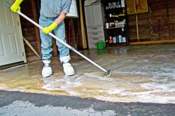 Un homme qui nettoie un sol béton