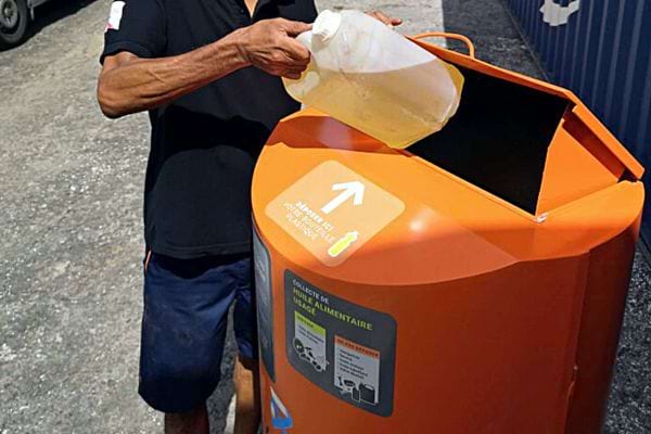 Une personne jetant un bidon d'huile dans une déchèterie orange 