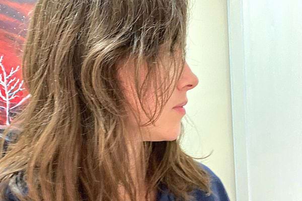 Une jeune femme ayant son visage de profil et en voyant globalement ses cheveux