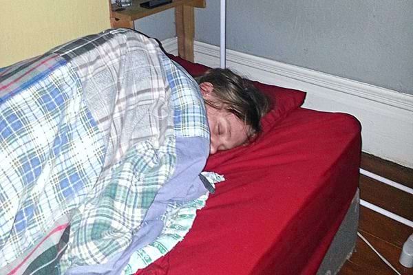 Une personne qui dort sur un drap rouge et une couverture à carreaux