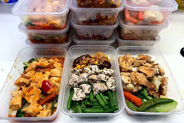 Plusieurs barquettes de repas sains avec du poulet et des légumes