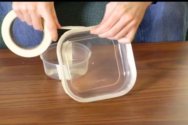 Une personne qui met du scotch sur une boîte en plastique