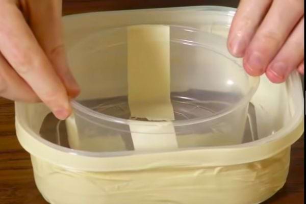 Une petite boîte en plastique avec du scotch dans une autre grosse boîte avec du scotch