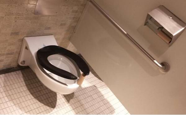 Un rouleau de pq entre les toilettes et la cuvette noire