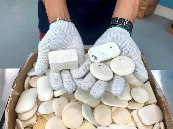 Une personne portant des gants blancs et ayant des savons d'hôtels dans les mains 