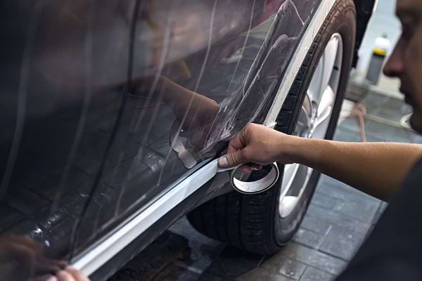 Un homme mettant du scotch sur une voiture