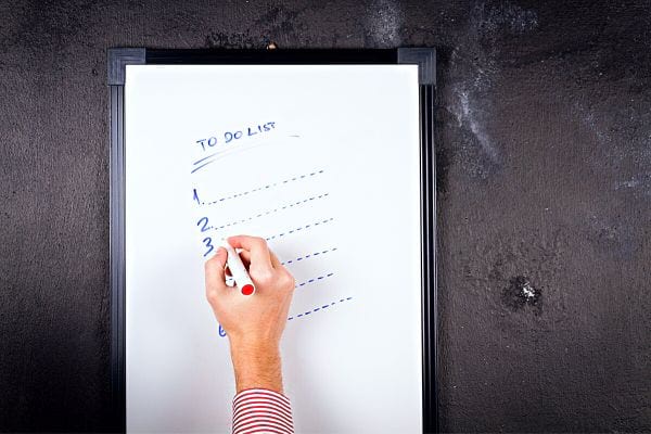 Une personne qui écrit une to do list sur une ardoise 