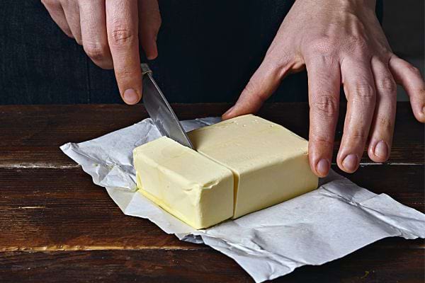 Une personne qui coupe une plaquette de beurre