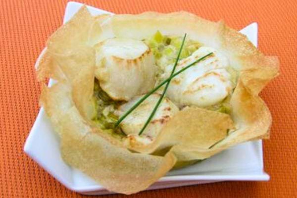 Une Brick aux noix de Saint-Jacques et à la fondue de poireaux dans une verrine blanche