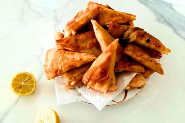 Des bricks au thon, pommes de terre et œuf sur de l'essuie-tout dans une assiette 