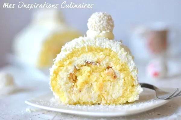 Une part de bûche blanche au Raffaello dans une petite assiette blanche avec une fourchette