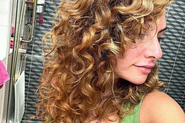 Une femme de profil avec les cheveux bouclés châtain clair