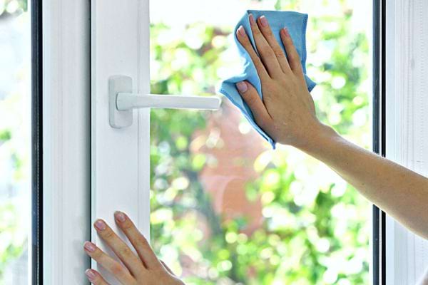 Une personne nettoyant une vitre avec un chiffon bleu