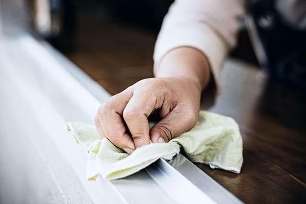 Une personne nettoyant une fenêtre avec un chiffon vert