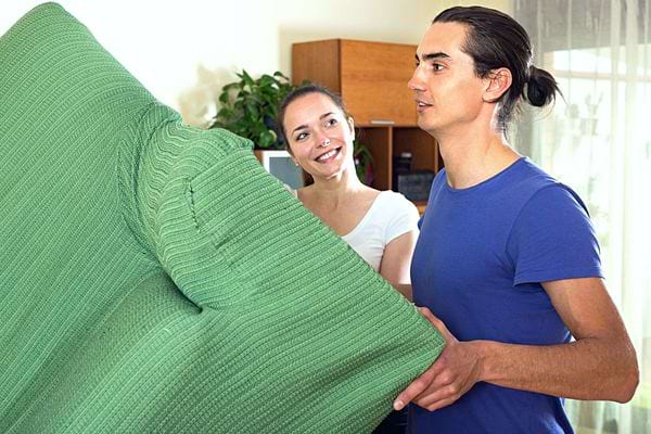 Un homme qui déplace un canapé vert 