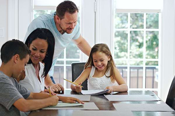 Une famille devant une table qui écrit 